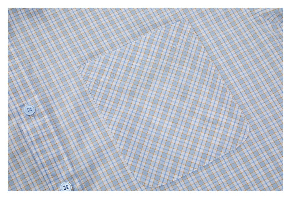 Close-up of a rounded chest pocket on a light blue and orange checked shirt, with part of the button placket visible.