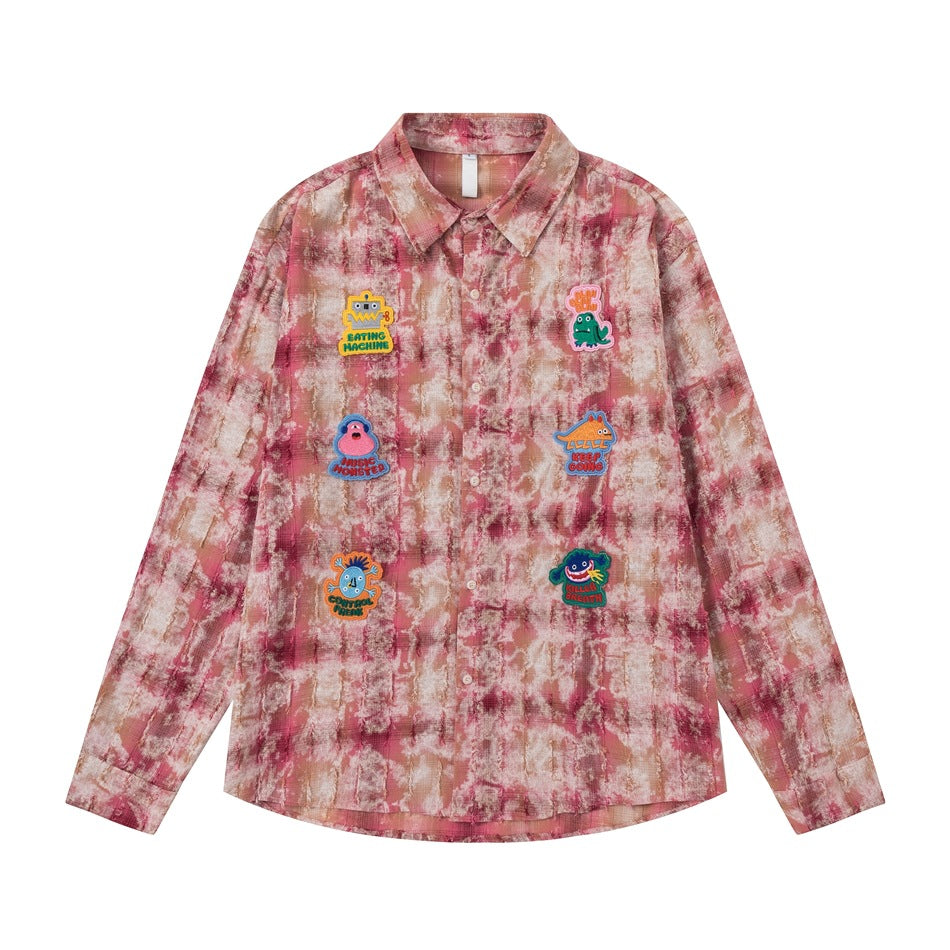 Pink tie-dye plaid long-sleeve button shirt with six embroidered cartoon monster patches, flat front view