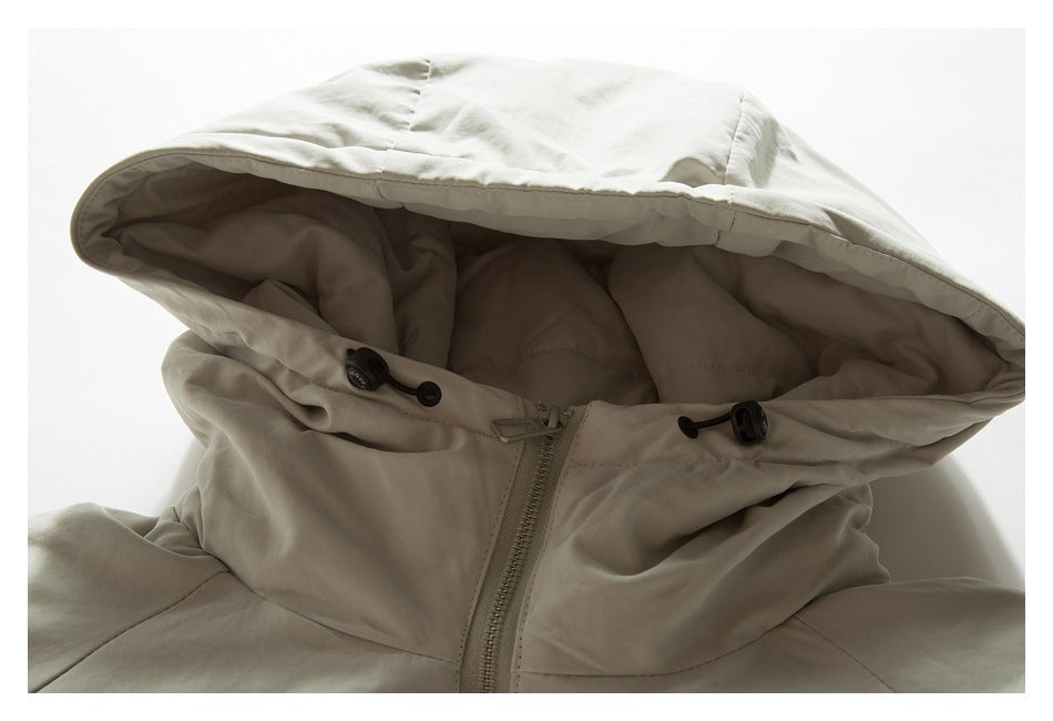 Close-up of a light beige hooded jacket showing the lined hood, drawcords, and front zipper.