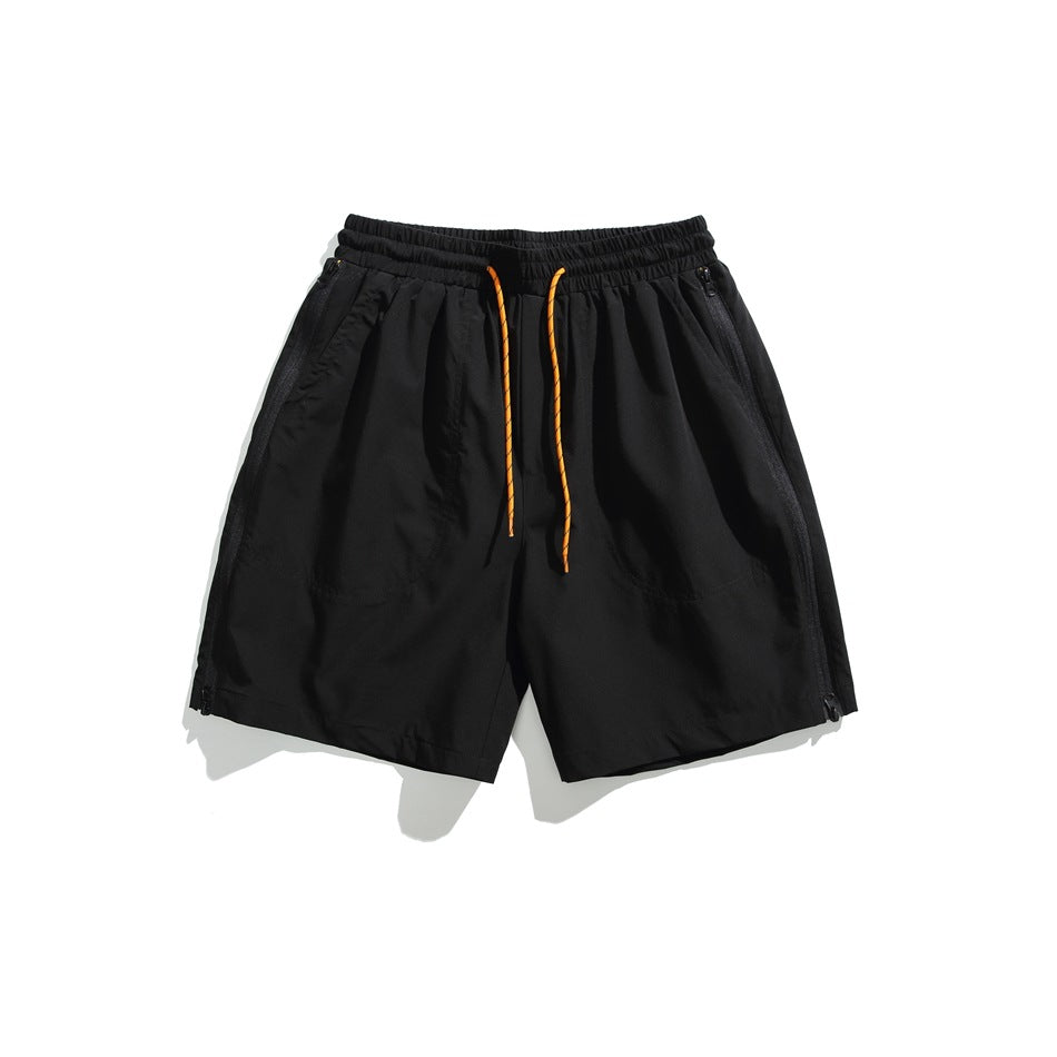 Front view of black shorts with an elastic waistband, orange drawstrings, zip pockets, and side zippers.