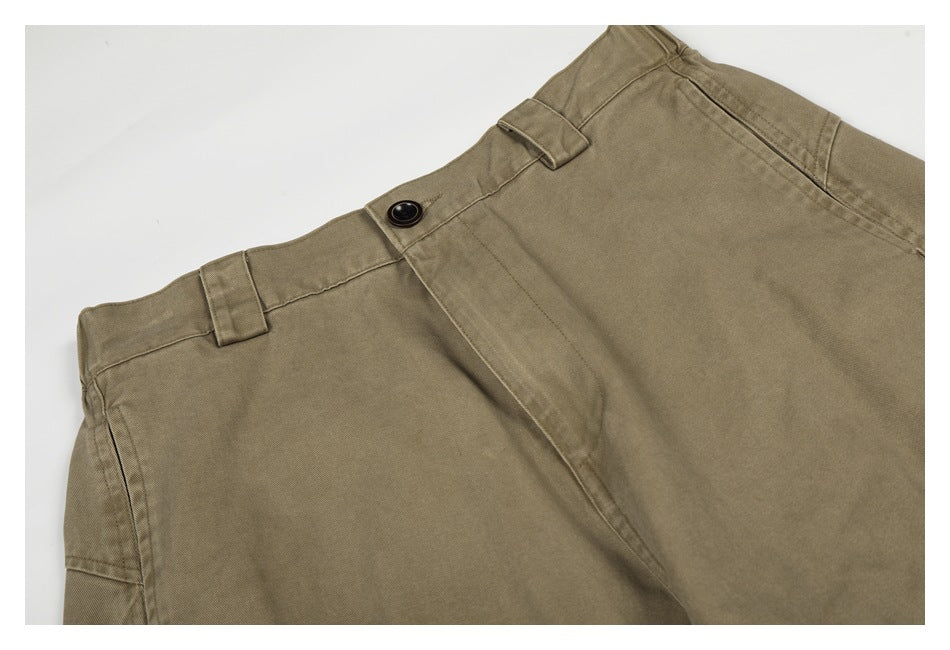 Close-up of the taupe trousers' front waistband, belt loops, button closure and pocket opening.