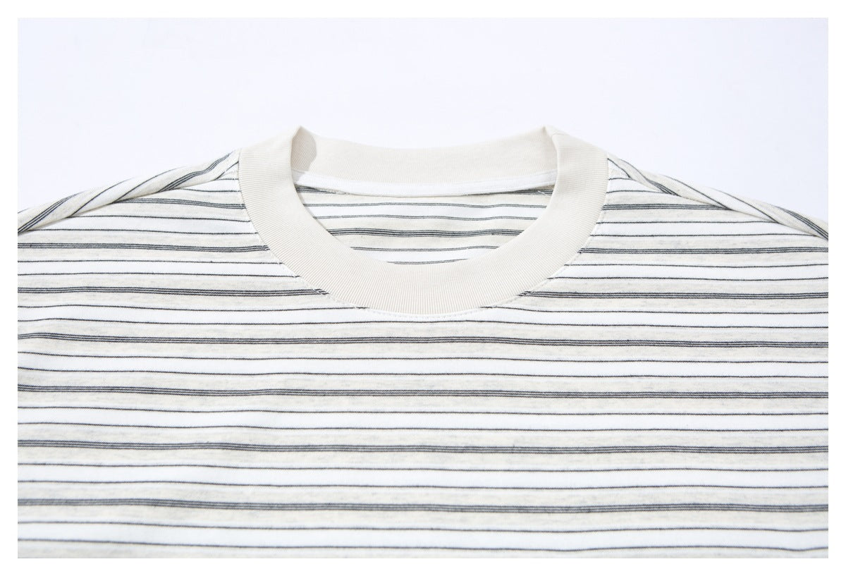 Close view of an ivory crew-neck shirt with thin dark horizontal stripes.