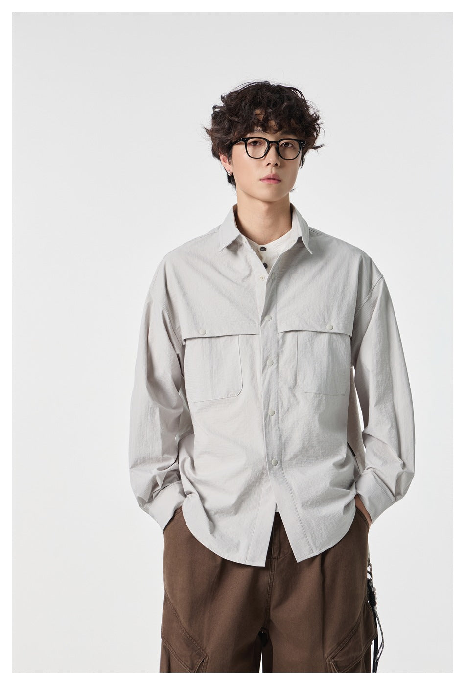 Closer view of a model wearing a light gray shirt with a pointed collar, snap buttons, and layered flap chest pockets.