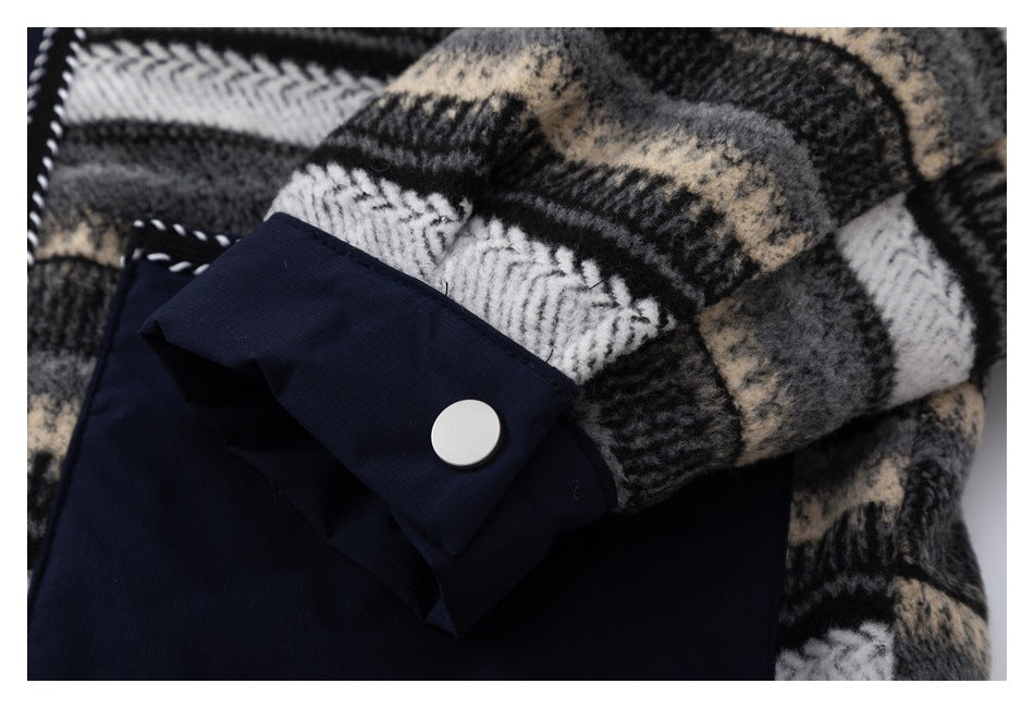 Close-up of a navy cuff tab with a silver snap against a black, gray, cream, and white plaid garment.