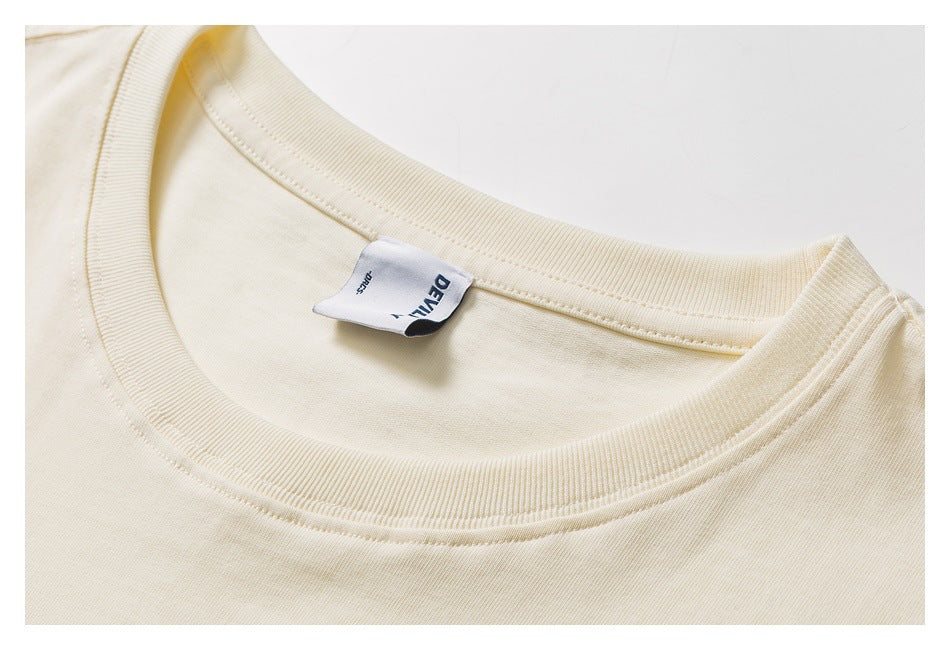 Close-up of the ivory T-shirt’s ribbed crew neck and inner brand label.