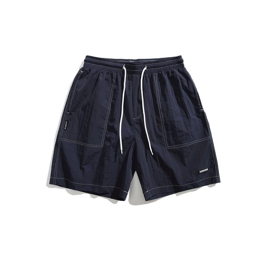 Navy drawstring shorts with white contrast stitching and large front pockets, flat lay front view