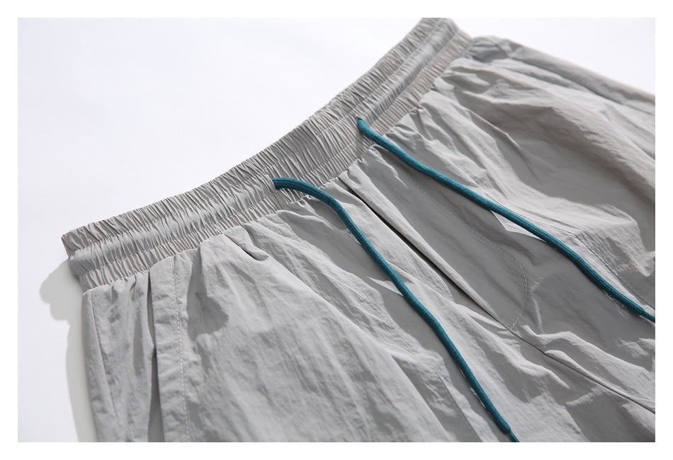 Close-up of light gray shorts showing the gathered elastic waistband and teal drawstrings.