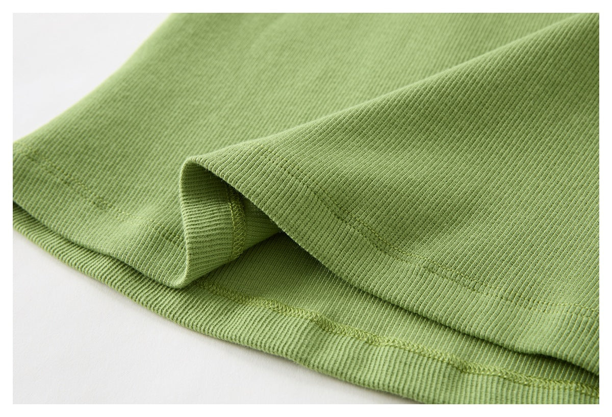 Close-up of the green ribbed top's folded hem, seam stitching, and fabric texture.