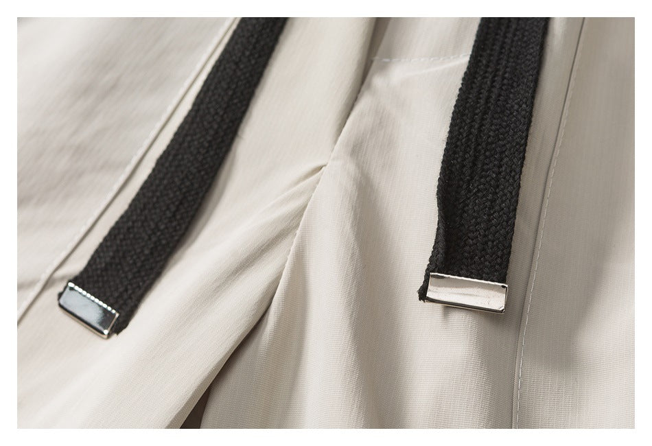 Close-up of black braided drawstrings with silver-tone metal tips against a light beige garment.