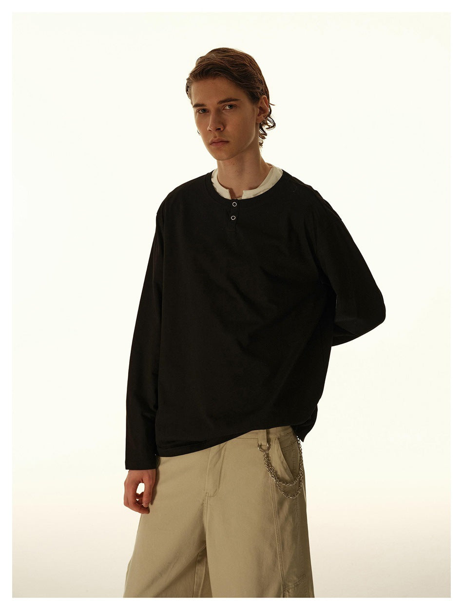 Man wearing a black long-sleeve henley top with white inner collar and snap placket, with khaki pants