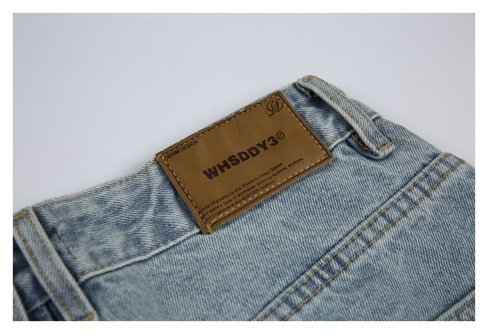 Close-up of a brown English-text leather patch on the waistband of light-wash jeans.