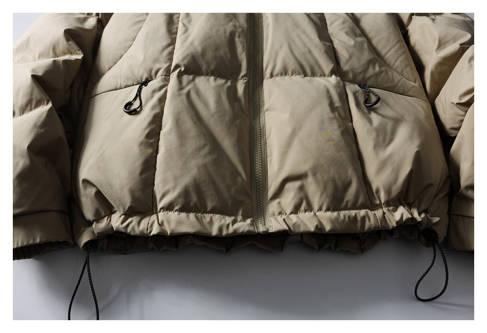 Cropped front view of a taupe jacket with a center zipper, two zippered pockets and adjustable hem cords.