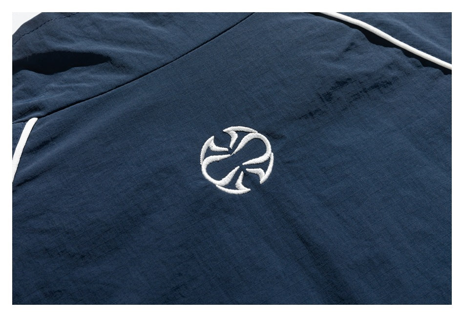 Close-up of a dark navy garment with white piping and a small white embroidered emblem.