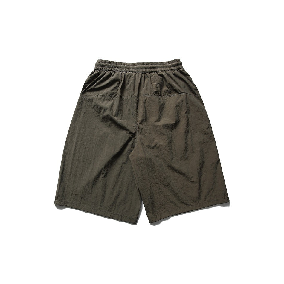 Back view of loose olive shorts with an elastic waistband and wide legs.