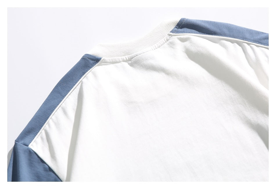 Close-up of the back shoulder area of a white T-shirt with blue panels along the shoulders and sleeves.
