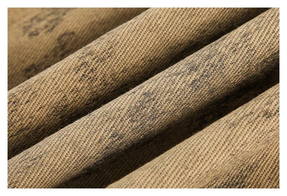 Macro view of textured tan fabric gathered into folds, with subtle dark mottling.