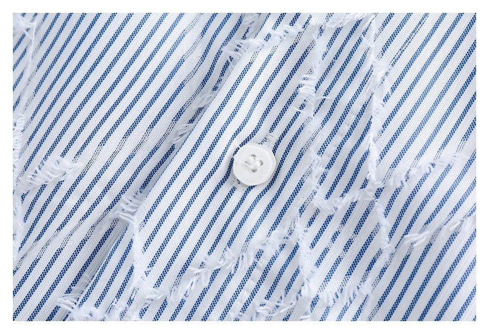 Close-up of a white button on blue-and-white striped fabric with frayed cutout detailing.