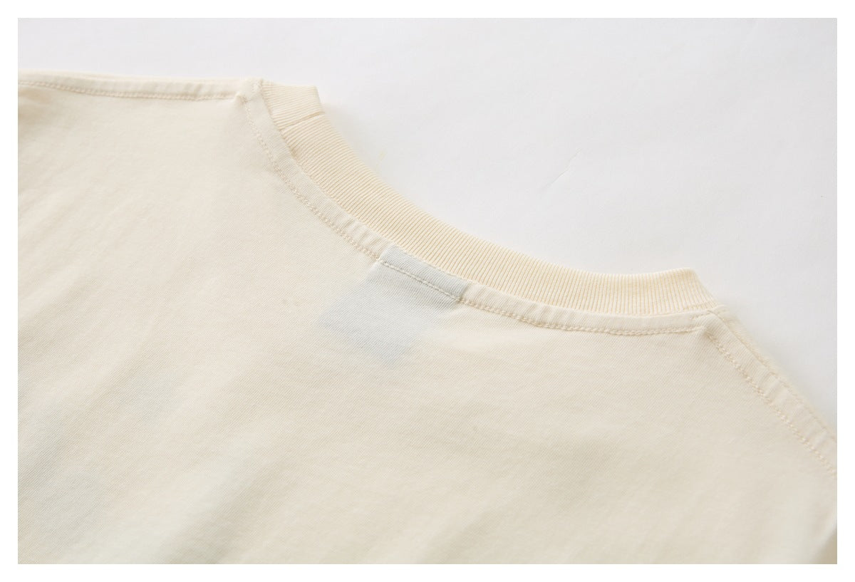 Close-up of the cream garment's ribbed crew neckline and shoulder seams.