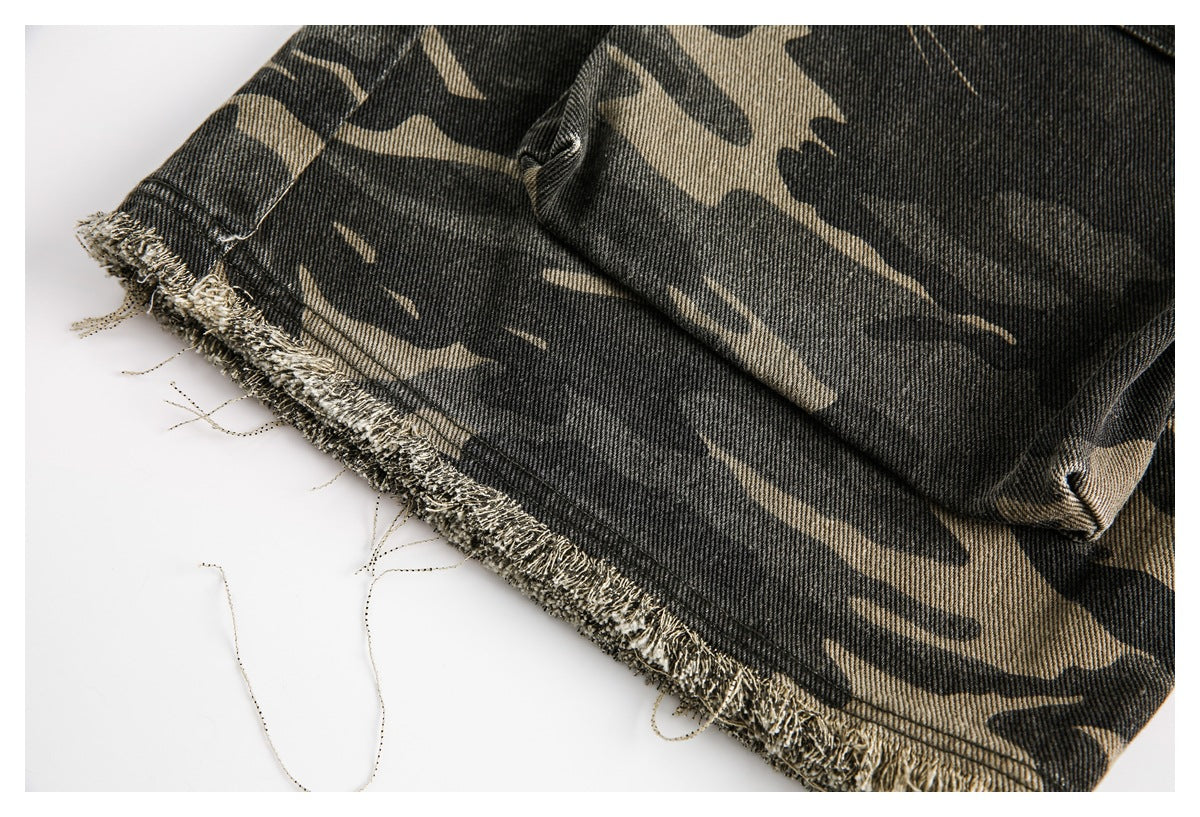 Close-up of camouflage trousers showing a raw, frayed hem and pocket stitching.