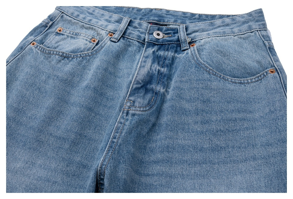 Close-up of light blue jeans showing the front waistband, button, fly, and curved pockets.