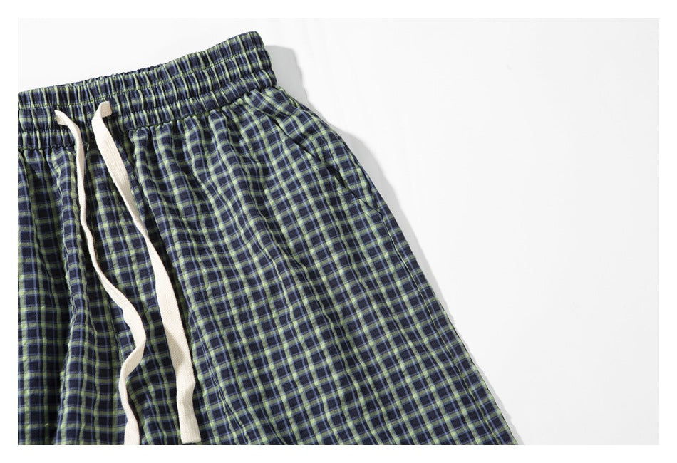 Close-up of the plaid shorts' elastic waistband, white drawstring, and side pocket.