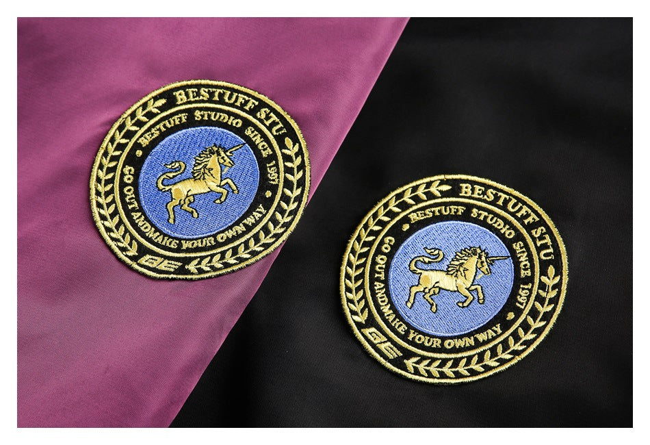 Embroidered circular unicorn patches on plum and black jacket fabric.