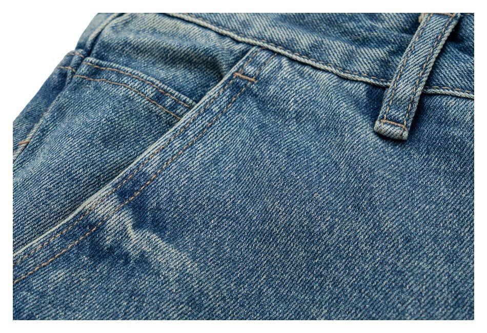Close-up of a blue denim jeans pocket, waistband seam, and belt loop.
