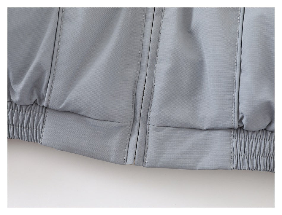 Close-up of the jacket's front zipper, stitched panels, and gathered elastic hem.