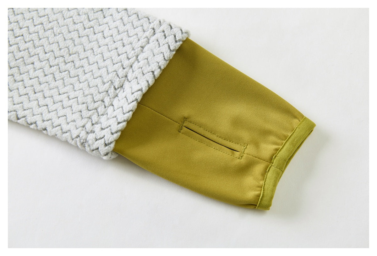 Close-up of a gray zigzag-patterned sleeve ending in a mustard-yellow cuff with a narrow slit pocket.