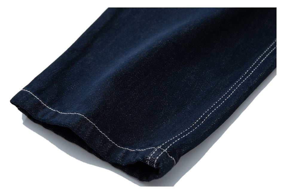 Close-up of dark indigo jeans hem with contrasting double stitching.