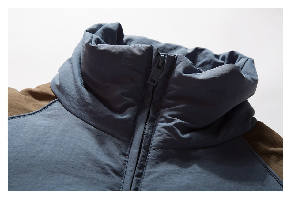 Close-up of a slate-blue jacket's raised collar and front zipper, with brown fabric behind it.