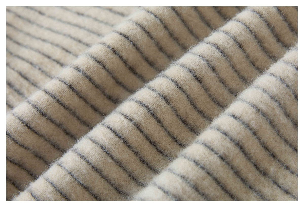 Macro view of fuzzy cream fabric with thin dark stripes and a soft, raised texture.