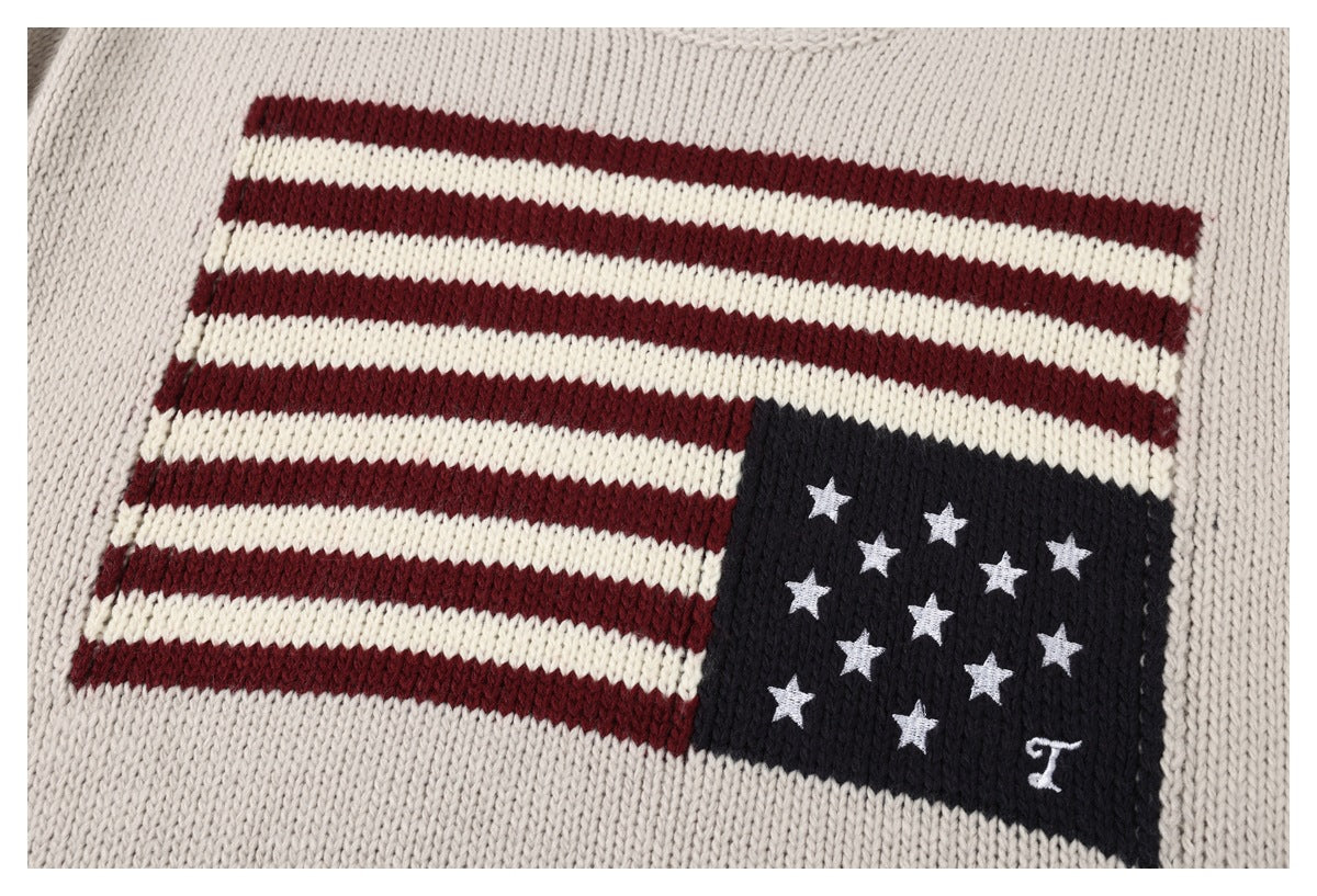 Close-up of a cream knit sweater with a red, cream, and navy flag motif and white stars.