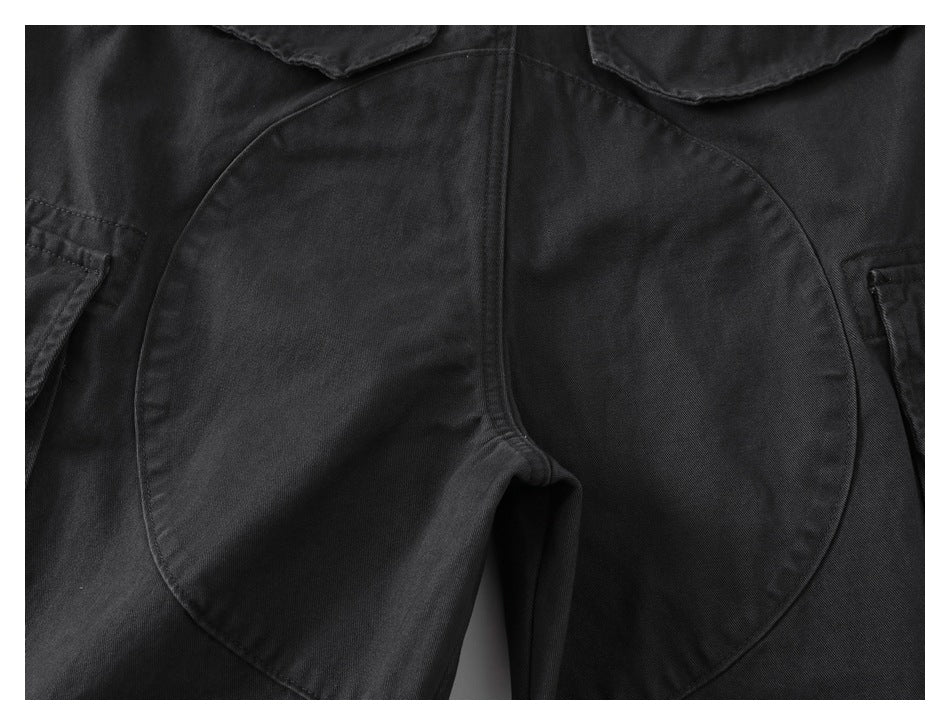 Close-up of black cargo pants showing a curved reinforced panel across the seat and crotch.
