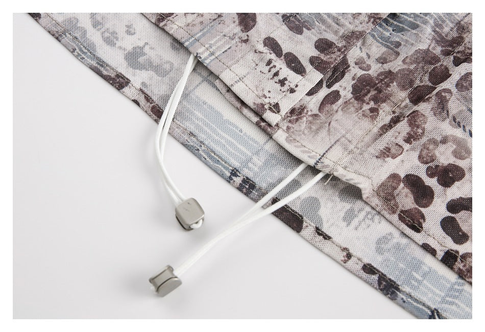Close-up of a printed garment hem with two white drawcords and gray cord locks.