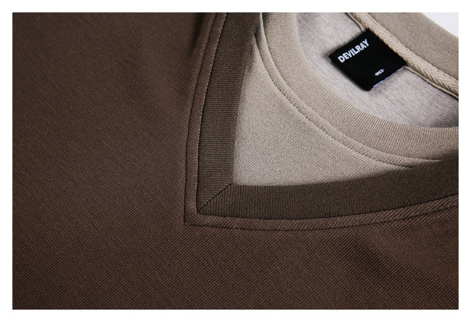 Tight detail of a brown top's layered neckline and black DEVILRAY label.