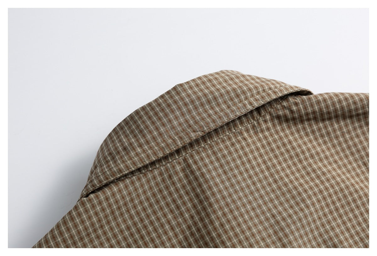 Close-up of the pointed collar and shoulder seam on a brown checked shirt.