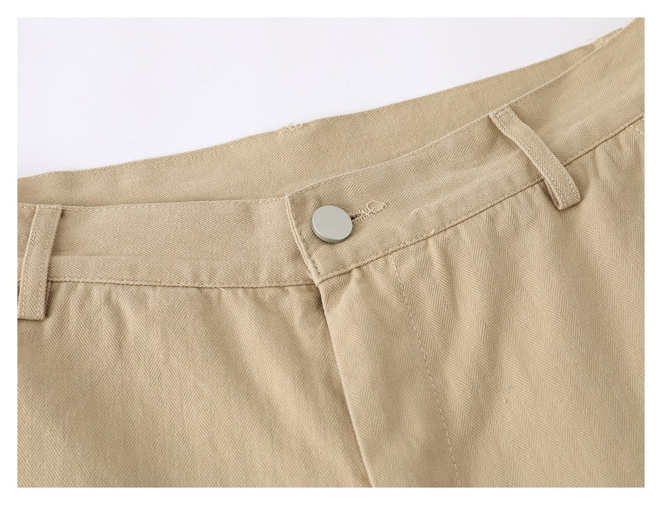 Close-up of the beige pants' waistband, button, belt loops, and fly stitching.