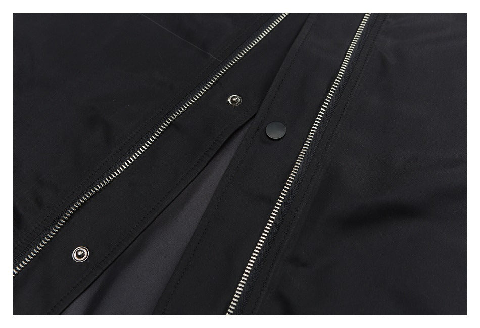 Close-up of a black garment with two silver zippers and a snap-button placket.