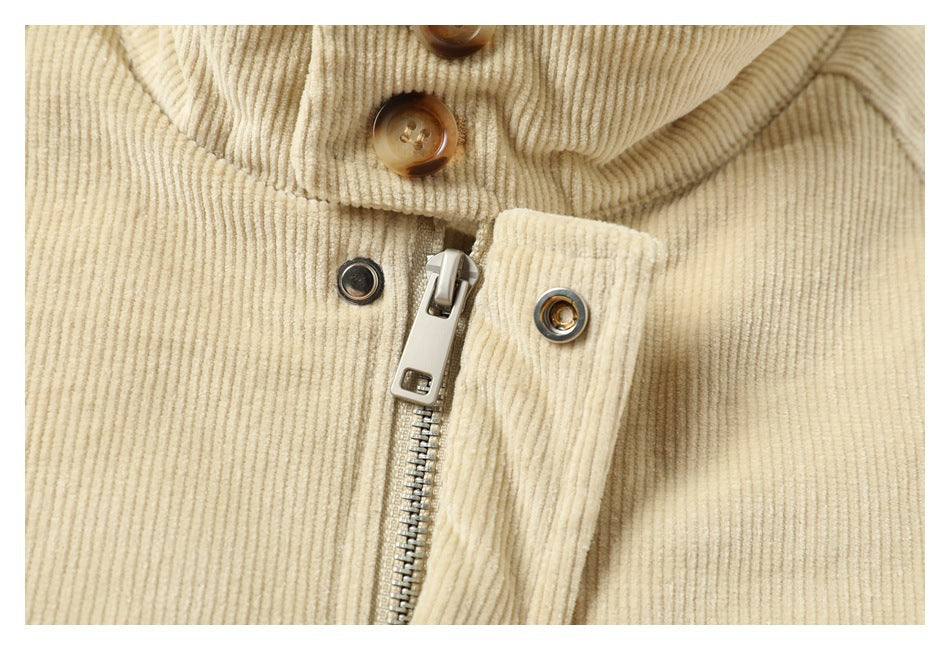Close-up of a cream corduroy jacket front with a metal zipper, snap fasteners, and brown buttons.