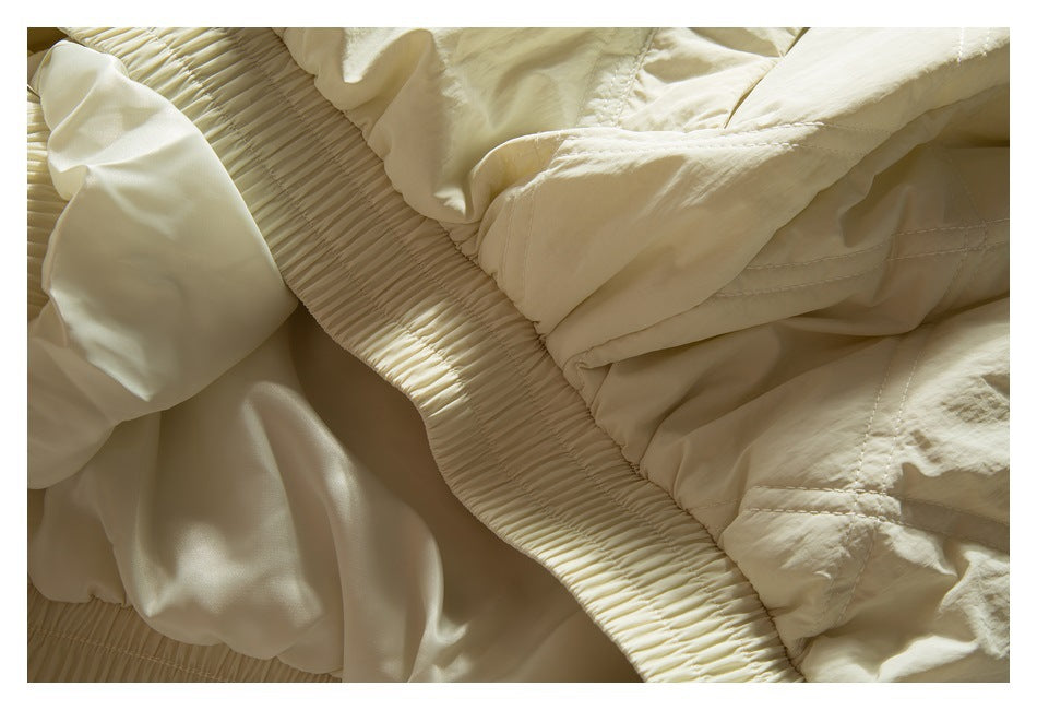 Close-up of the ivory jacket's gathered elastic hem and smooth inner lining.