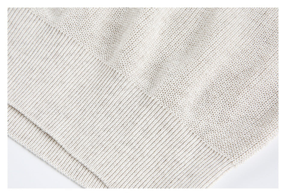 Close-up of an ivory knit sweater hem with wide ribbed edging.