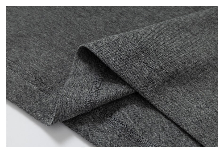 Close-up of folded gray garment fabric showing the hem and overlock stitching.