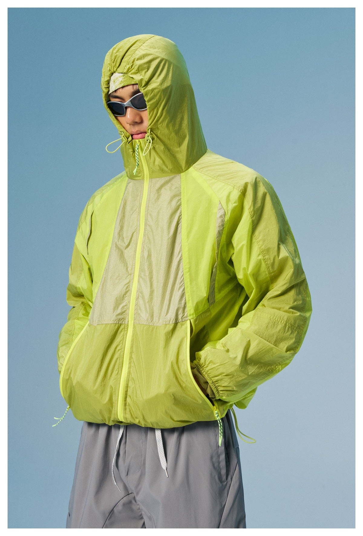 Model wearing a lime-green color-block jacket with the adjustable hood pulled up.