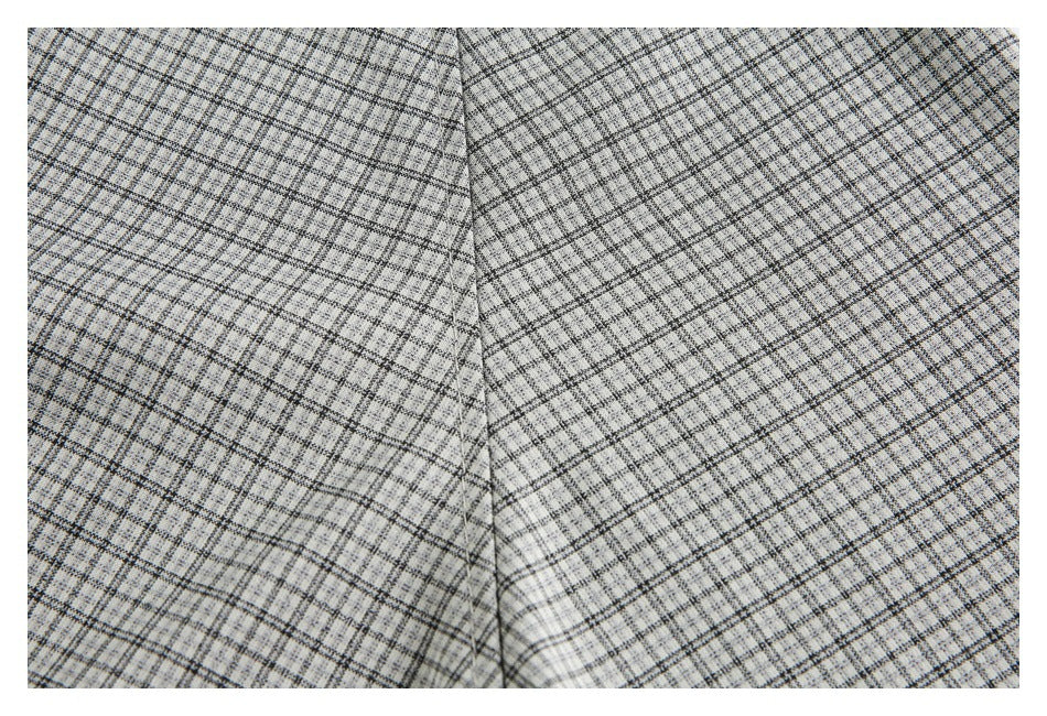 Close-up of light gray plaid fabric showing a vertical seam and intersecting black lines.