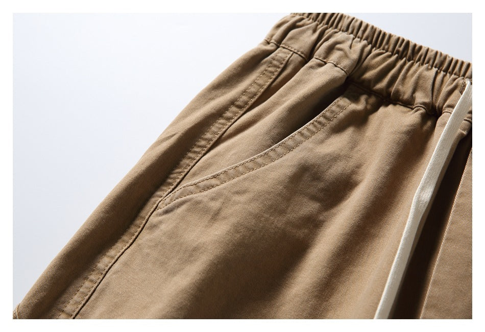 Close-up of tan bottoms showing the gathered elastic waistband and a slanted front pocket.