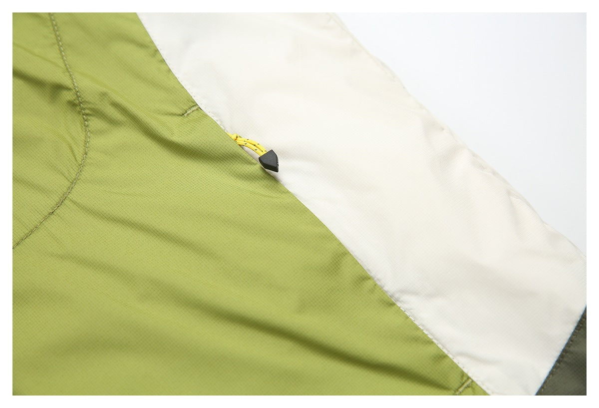 Close-up of a yellow drawcord toggle at the seam between lime-green and white garment panels.