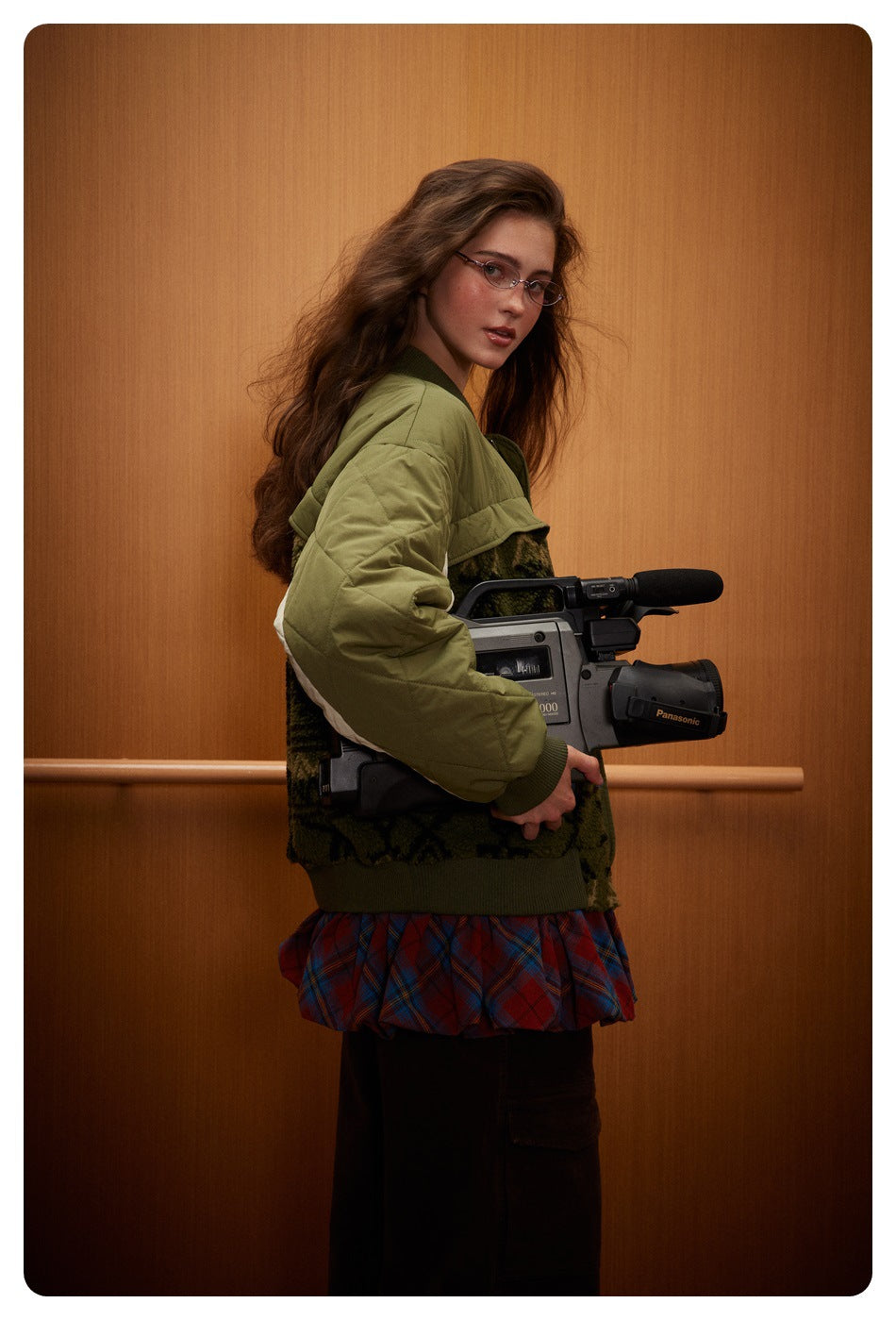 Side view of a model wearing an olive quilted bomber jacket with a dark patterned body and cream sleeve panels.