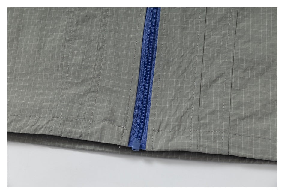 Close-up of a blue zipper and stitched panels on gray grid-patterned fabric.