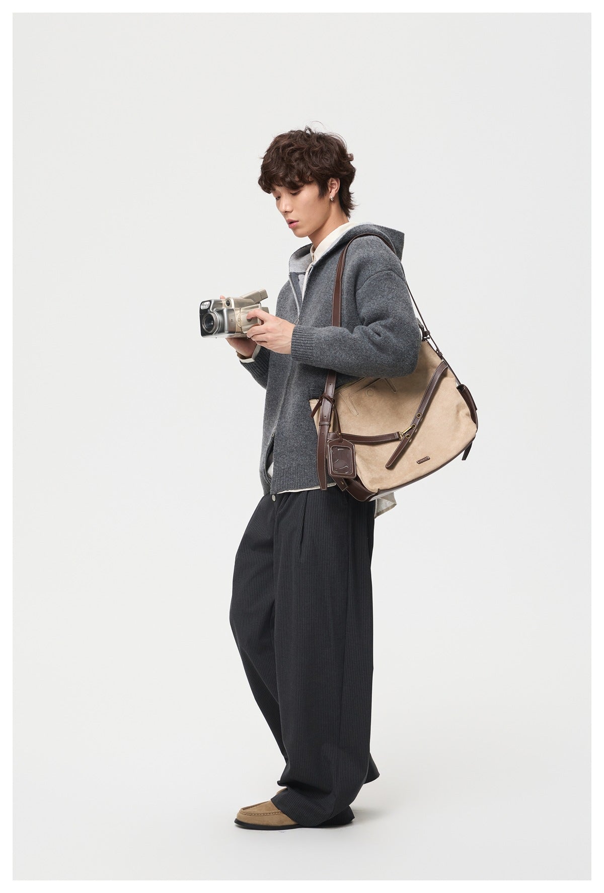 Model wearing a charcoal gray hooded zip jacket with ribbed cuffs and hem, paired with dark trousers.